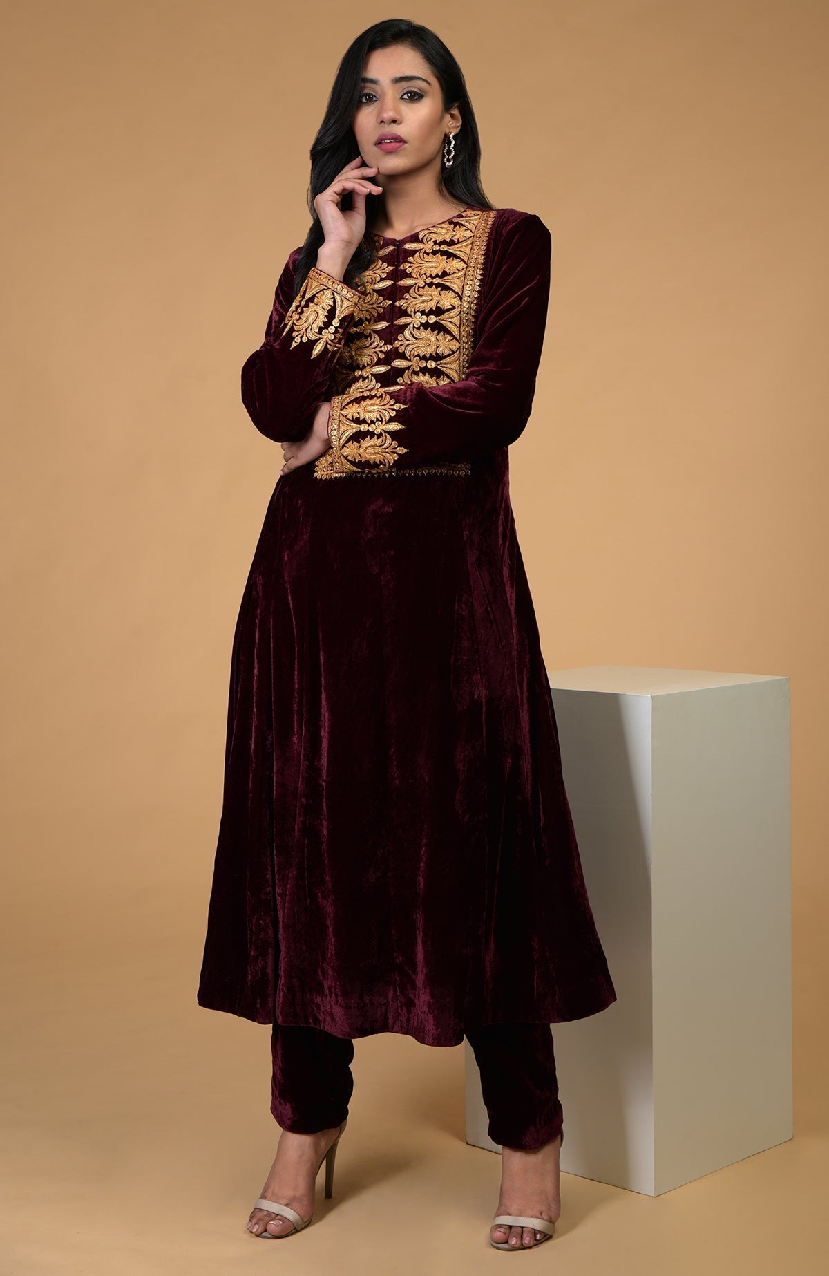 A woman models a rose maroon gold Kashmiri tilla embroidered kurta set.