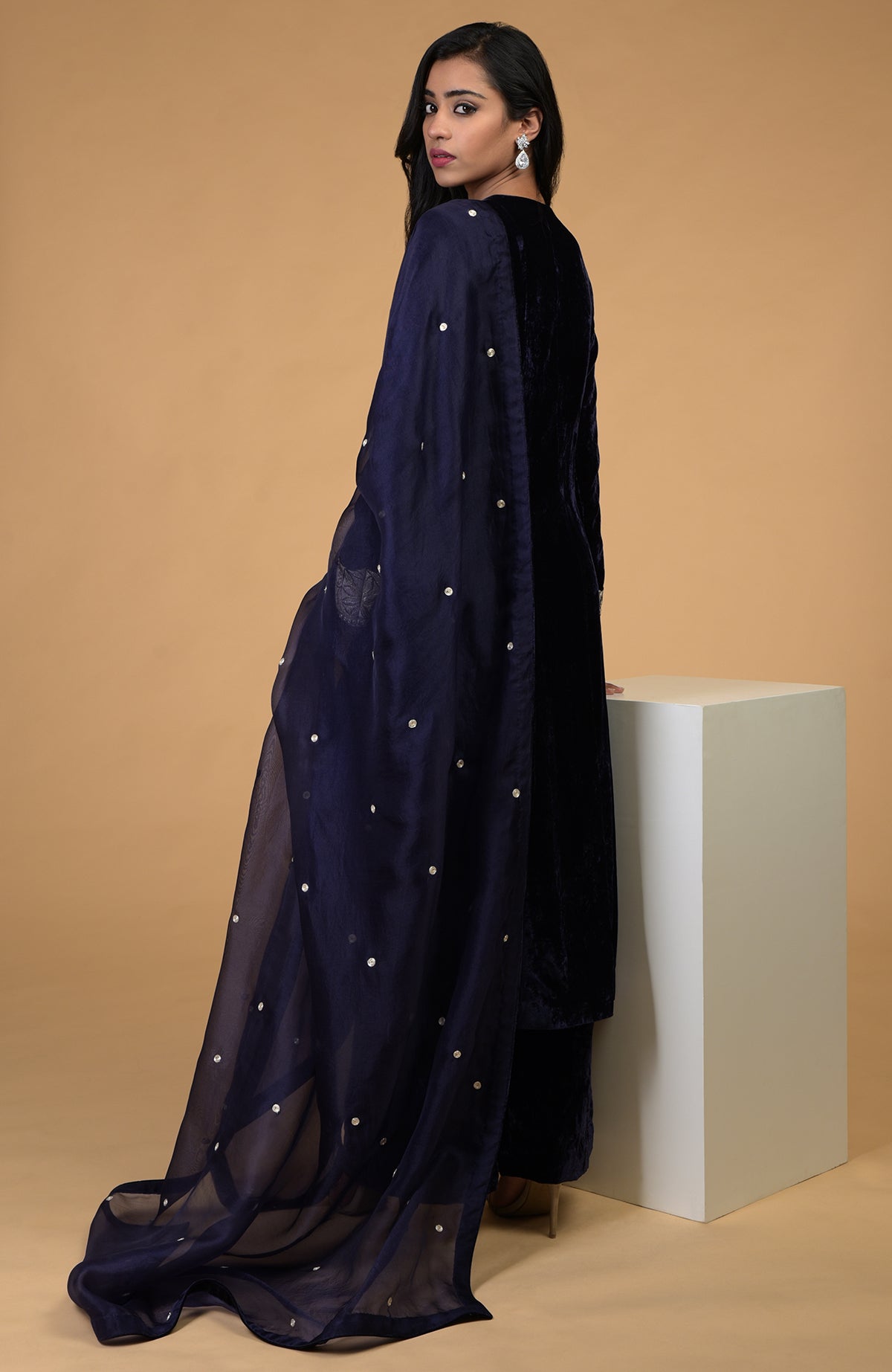 A woman models a midnight blue velvet kurta set with a sheer dupatta.