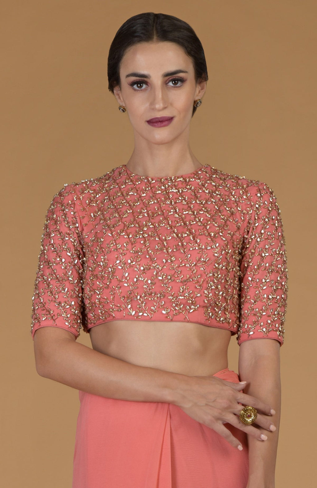 A woman models a salmon pink saree and a matching hand-embroidered blouse.