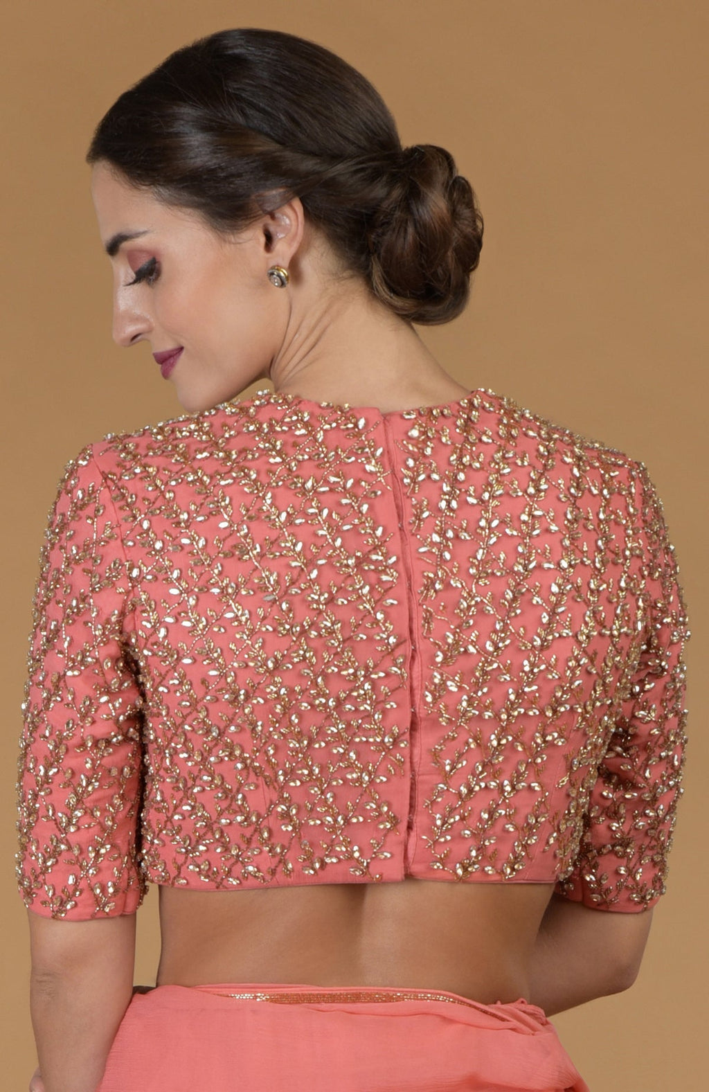 Salmon pink blouse with gold and silver bead embroidery, paired with a matching saree.