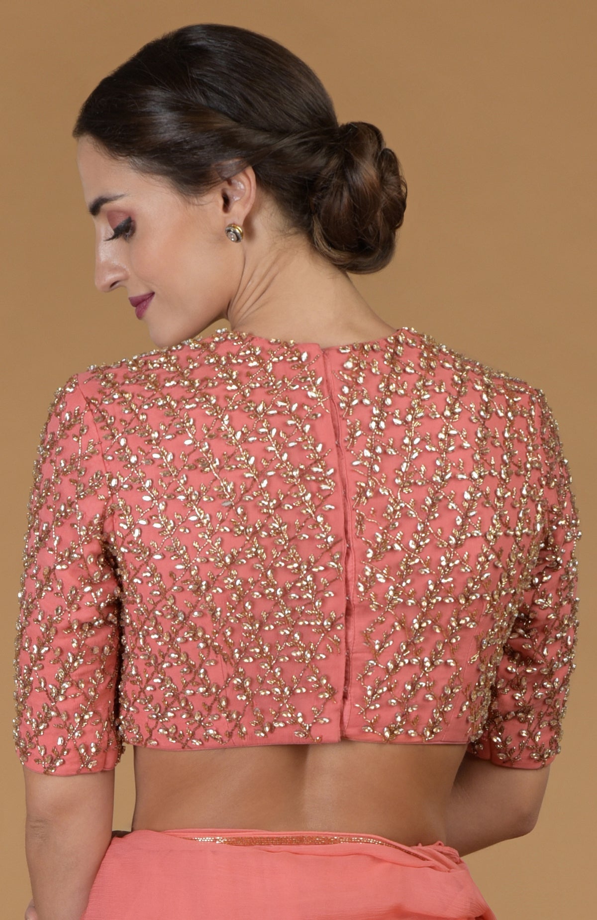 Salmon pink blouse with gold and silver bead embroidery, paired with a matching saree.