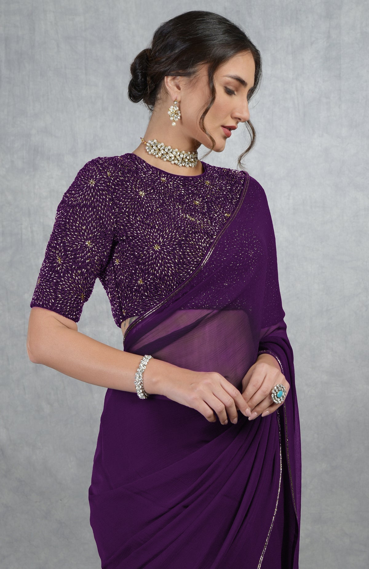 Plum purple gold hand embroidered saree and blouse with a woman posing.