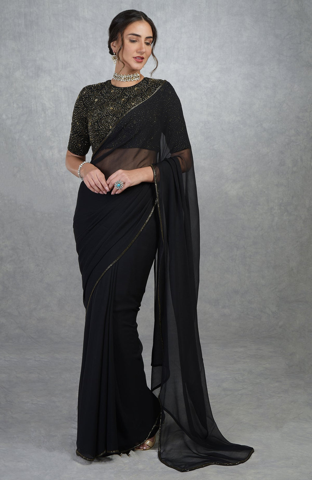 A woman models a black and gold hand-embroidered saree and blouse.
