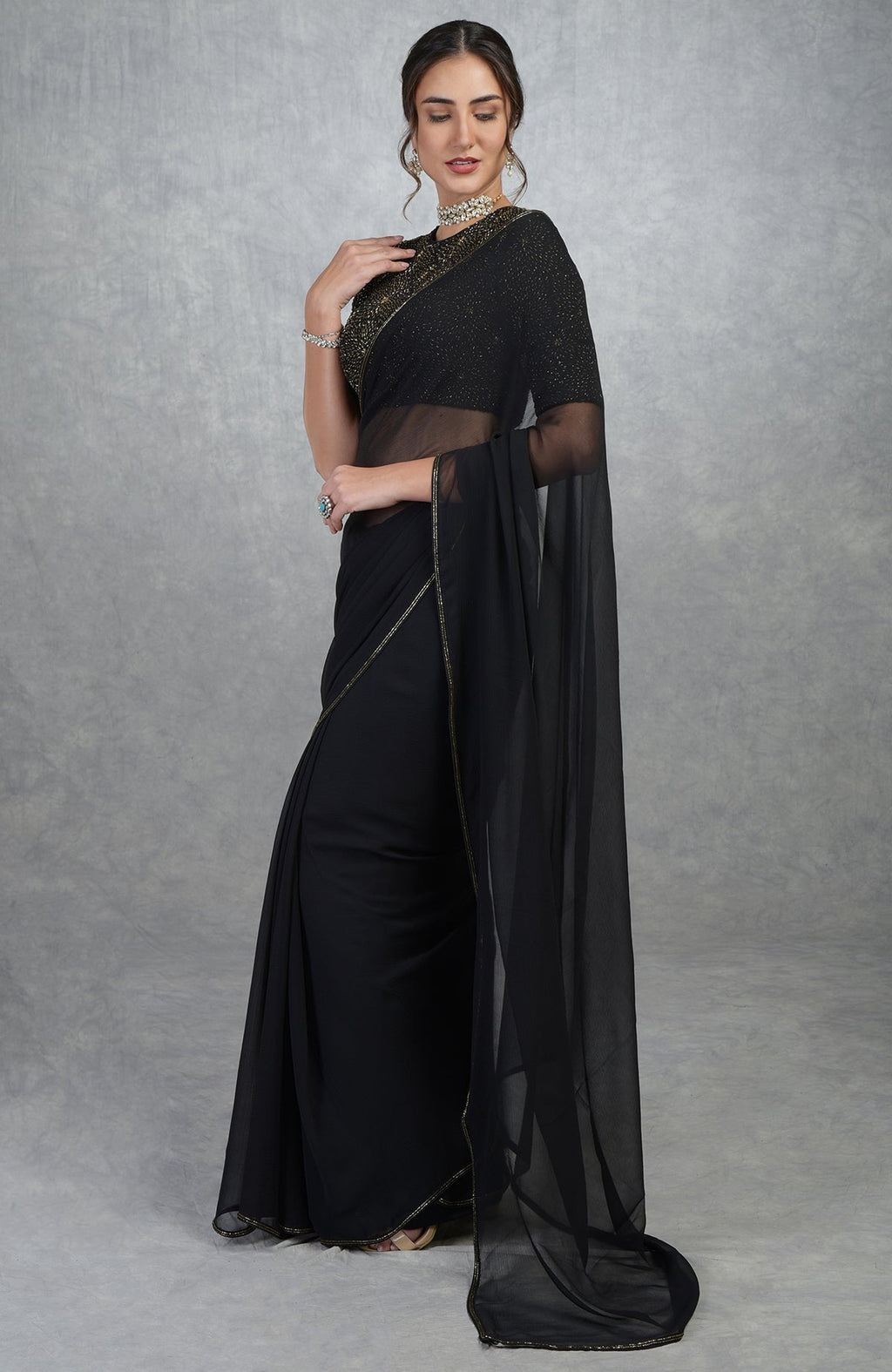 A woman models a black and gold hand-embroidered saree and blouse.