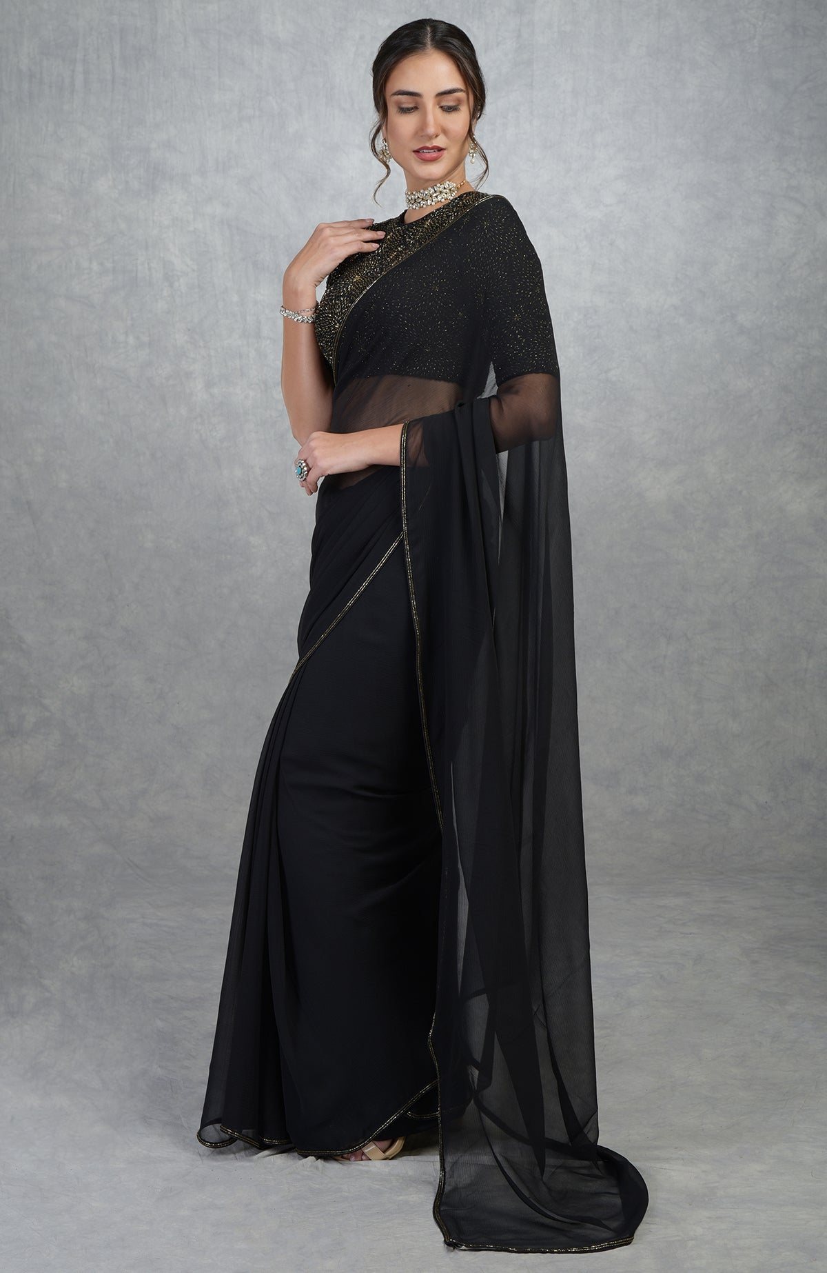 A woman models a black and gold hand-embroidered saree and blouse.