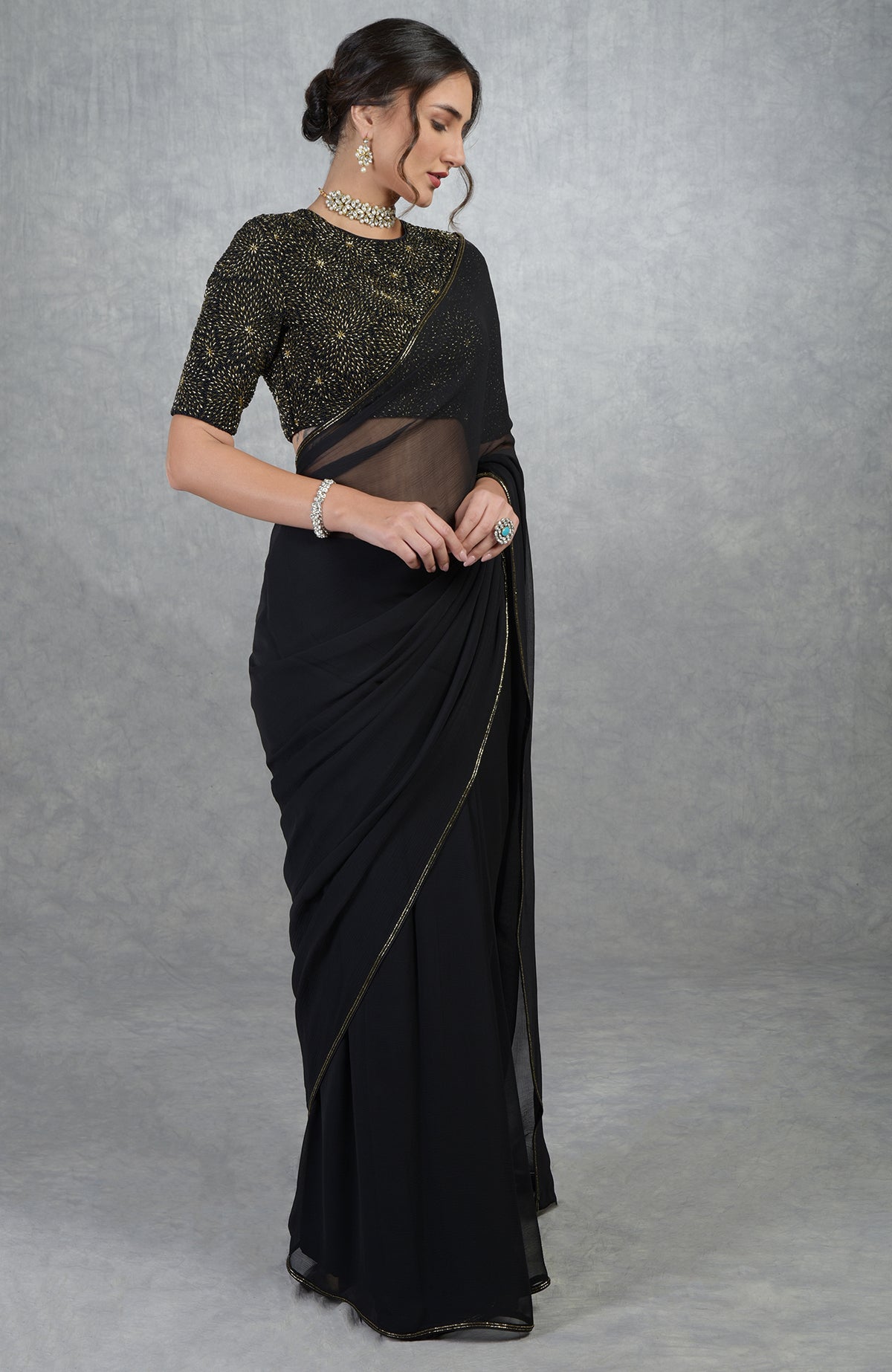 A woman models a black and gold hand-embroidered saree and blouse.