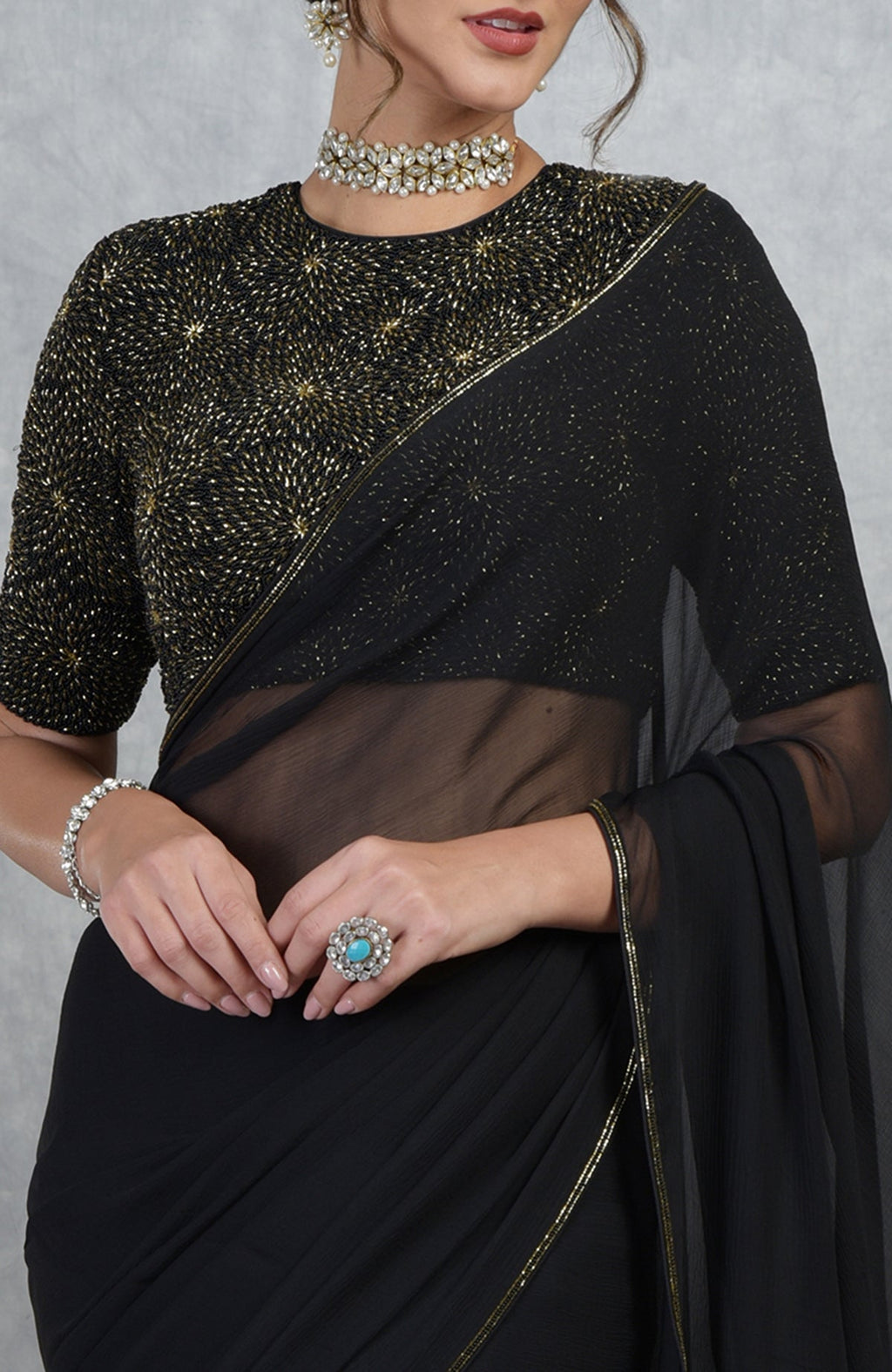 Black gold hand embroidered saree and blouse with a choker and ring.