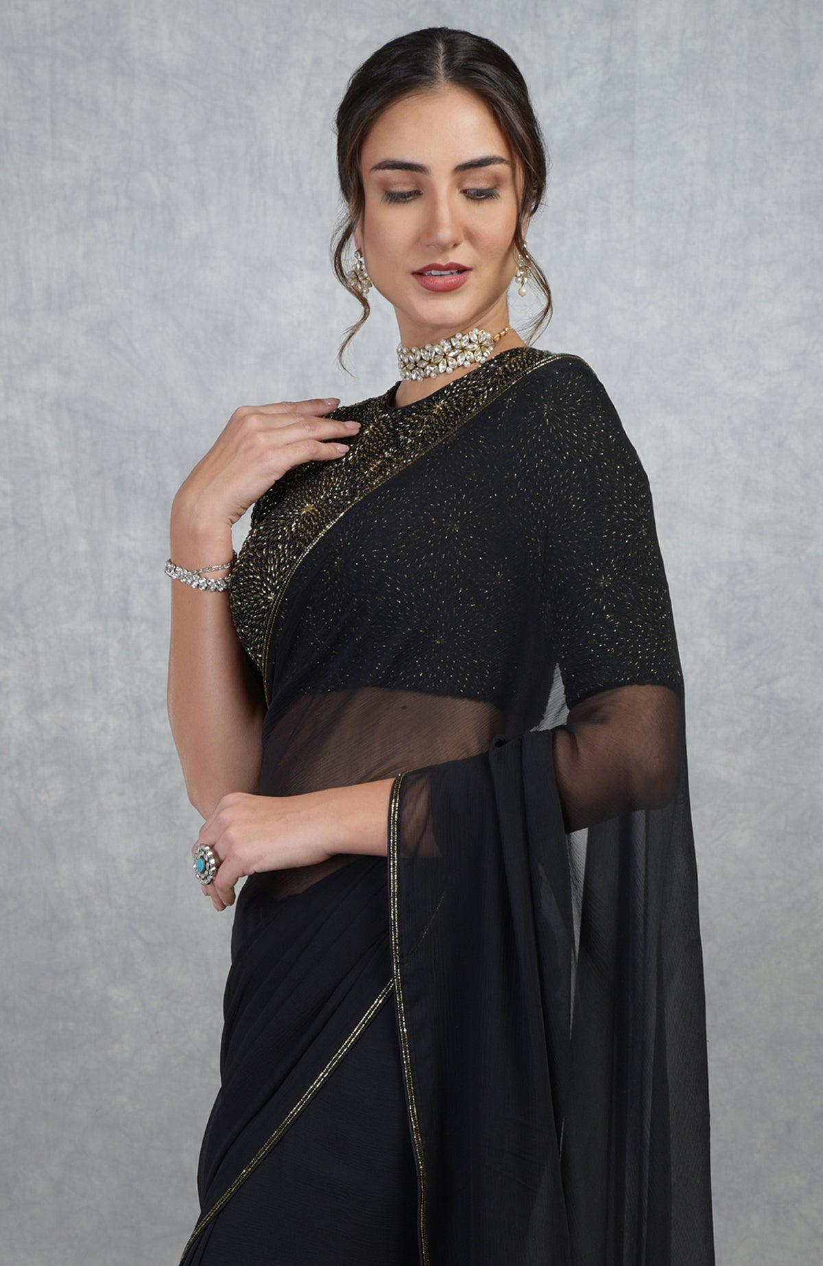 Black gold hand embroidered saree and blouse with a woman posing.