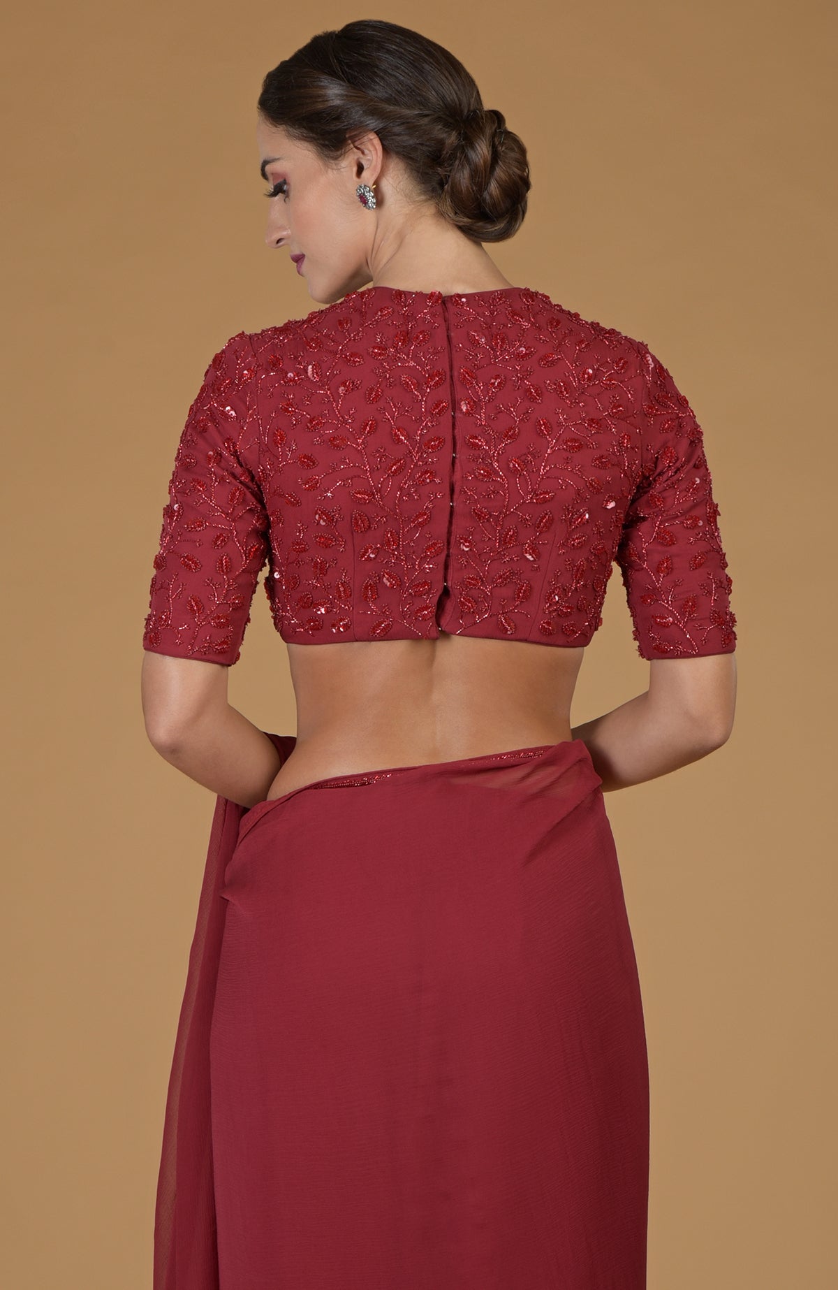 A woman from behind wears a red foliage hand-embroidered saree and blouse.