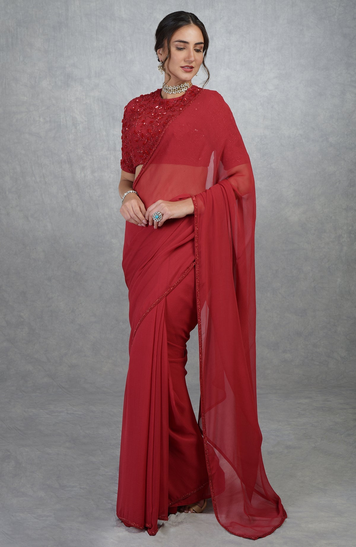 Red chiffon silk saree with a hand-embroidered blouse featuring beads and sequins.