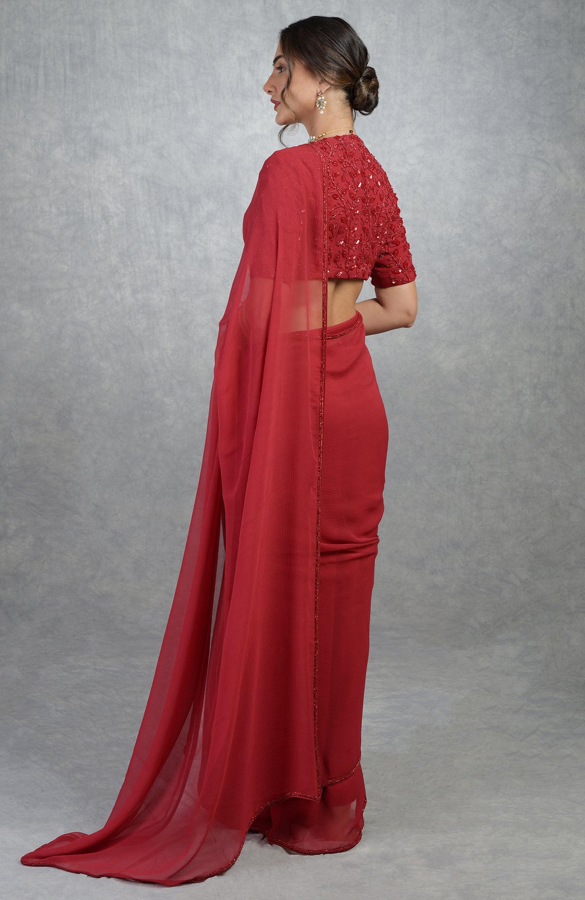 A woman models a red hand-embroidered saree and blouse with a beaded border.