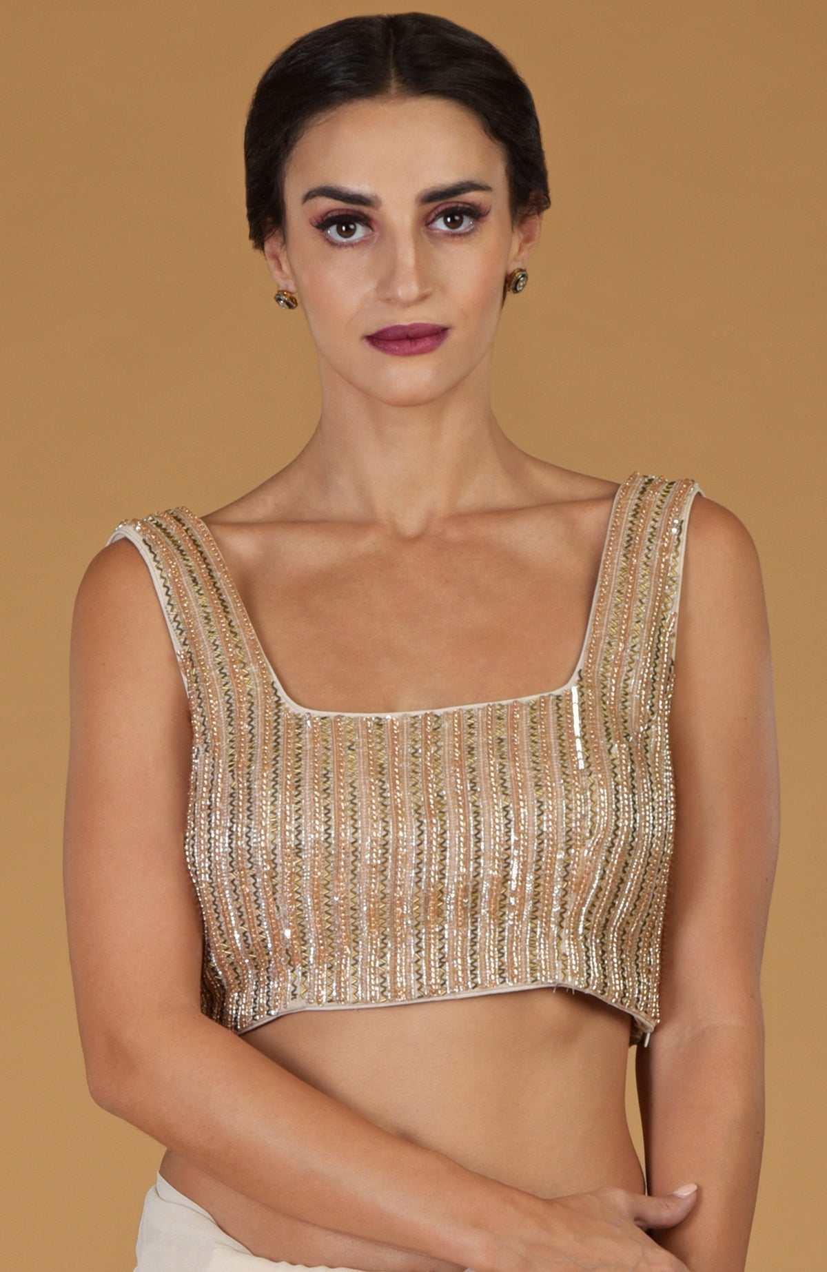 A woman models a champagne gold hand-embroidered blouse with a square neckline.