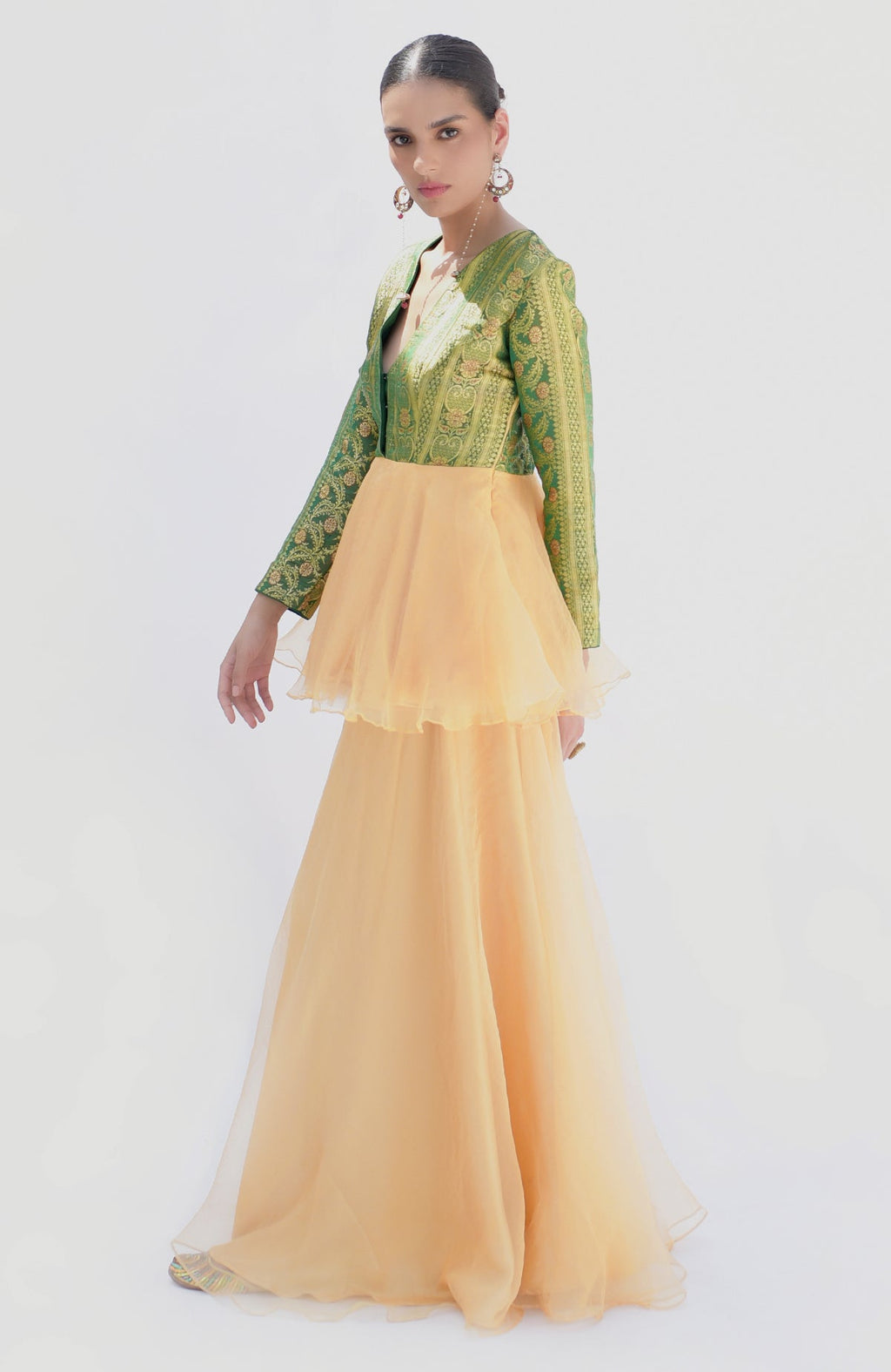 A woman models a green Banarasi peplum top with a gold sharara.
