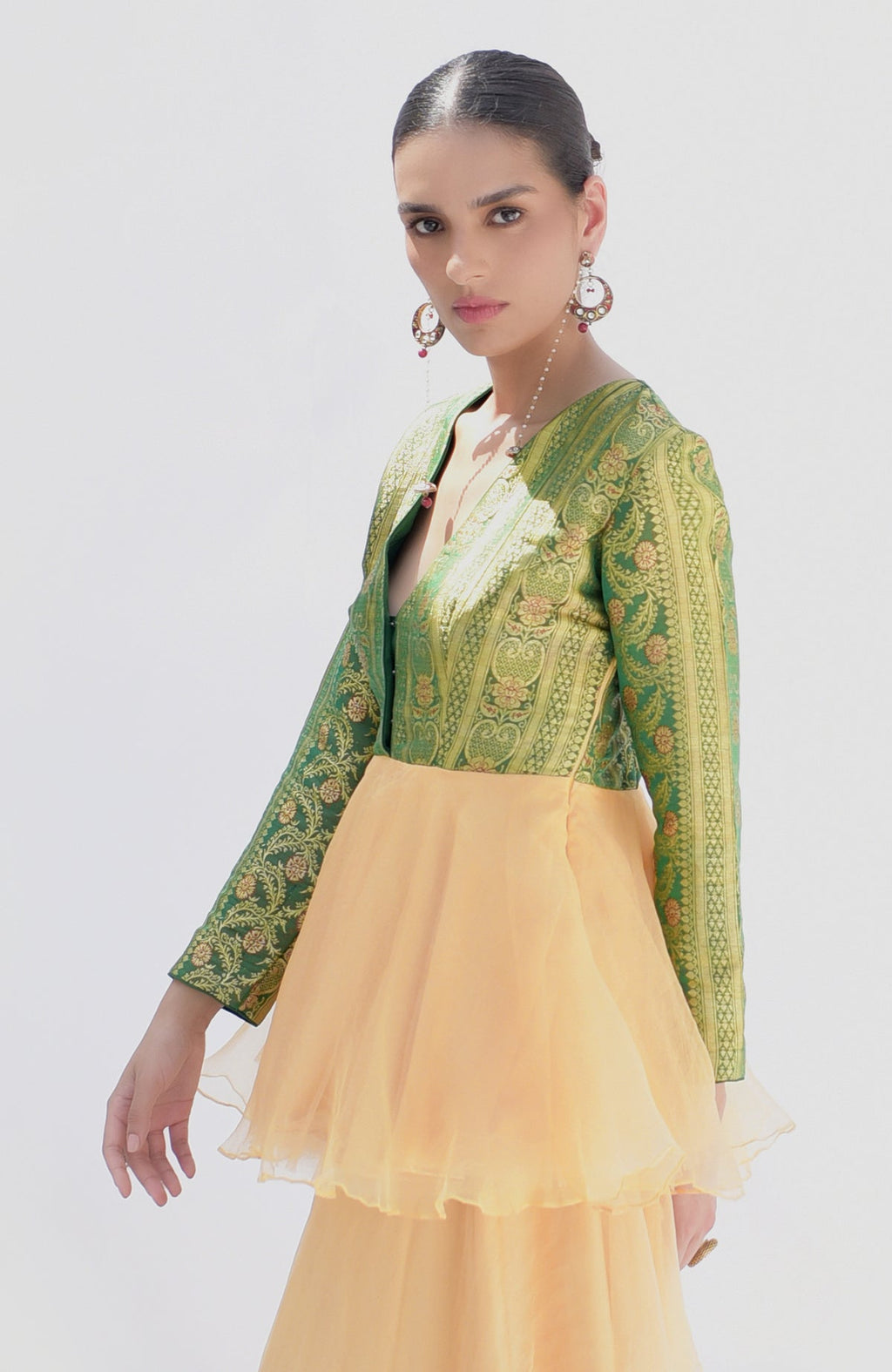 A woman models a green Banarasi handwoven peplum top with a gold sharara.