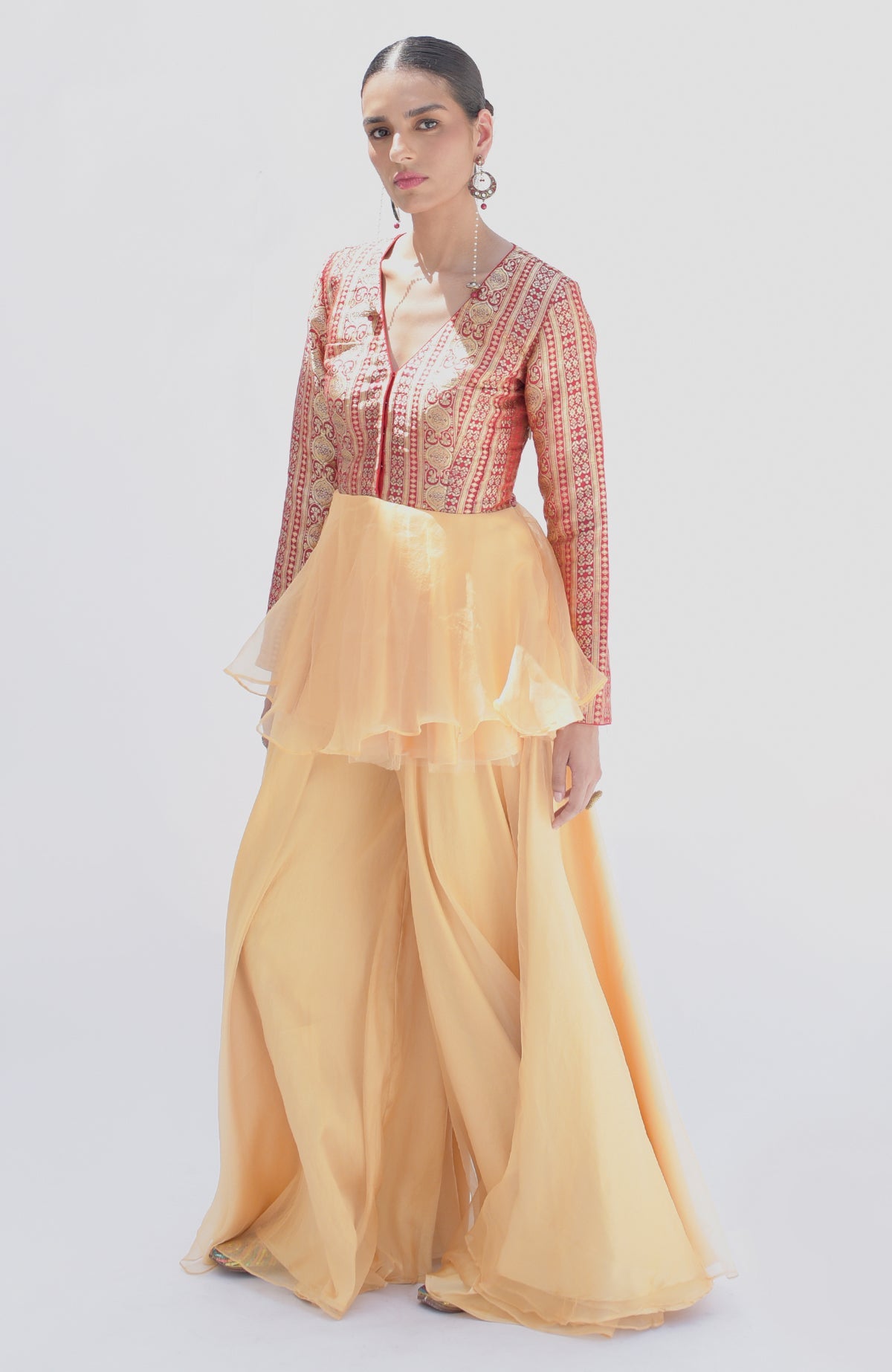 A model wears a red and gold Banarasi peplum top with a gold sharara.