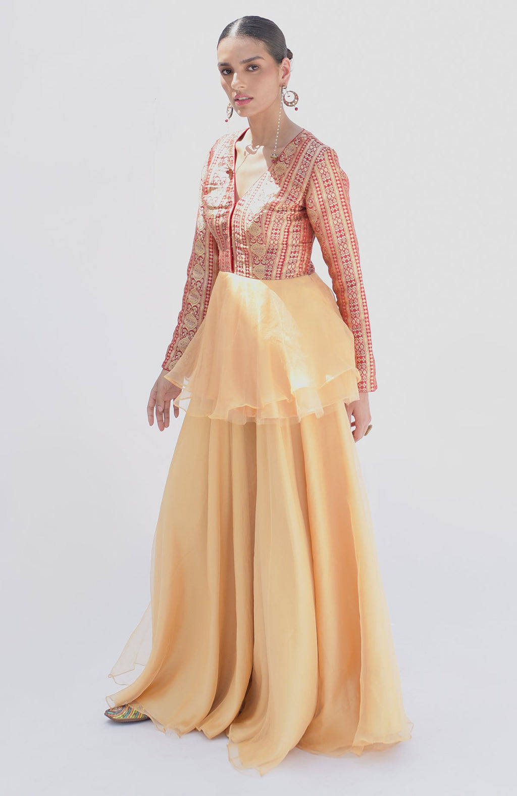 A model wears a red and gold peplum top with a flowing gold sharara.