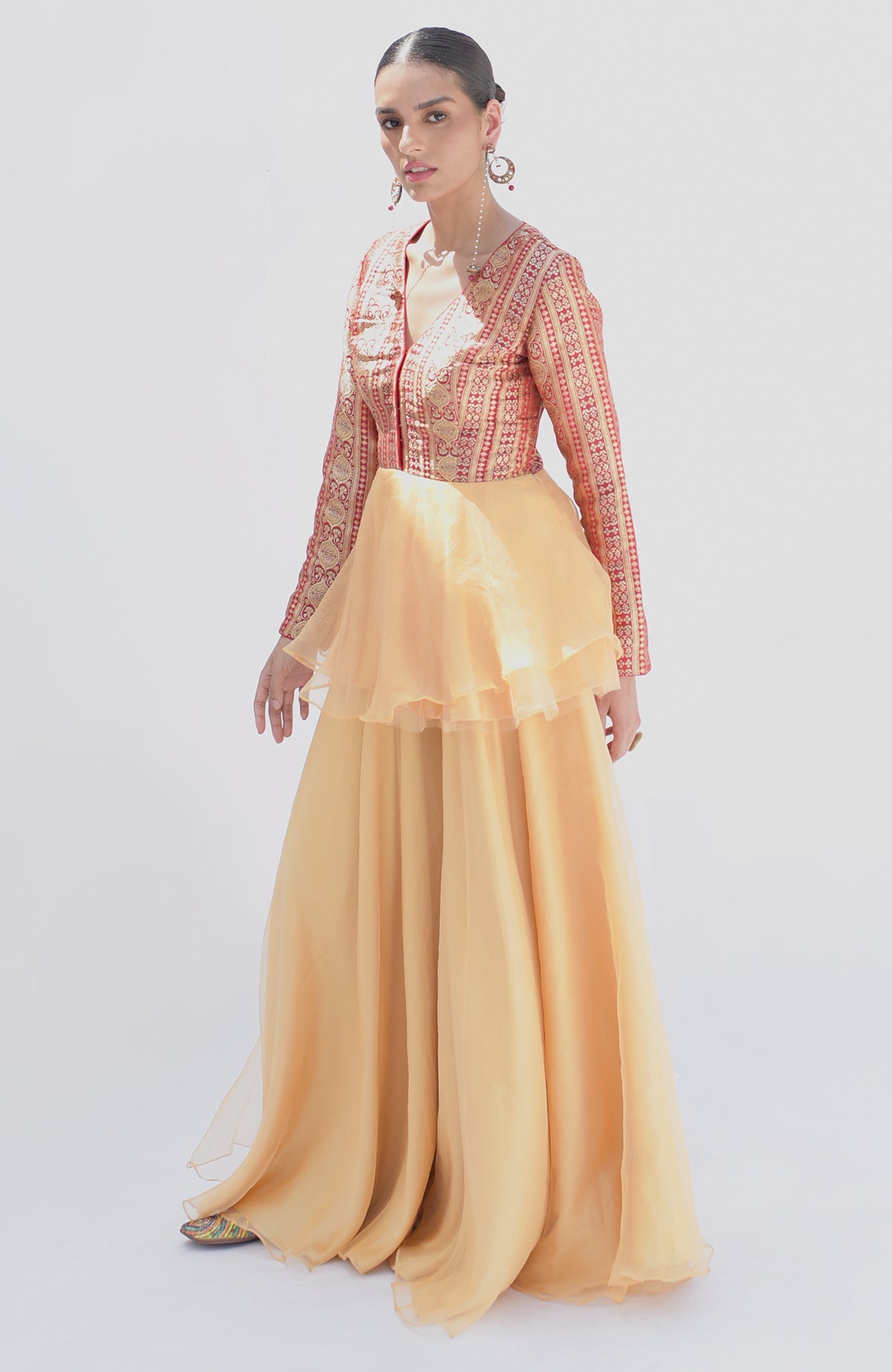 A model wears a red and gold peplum top with a flowing gold sharara.