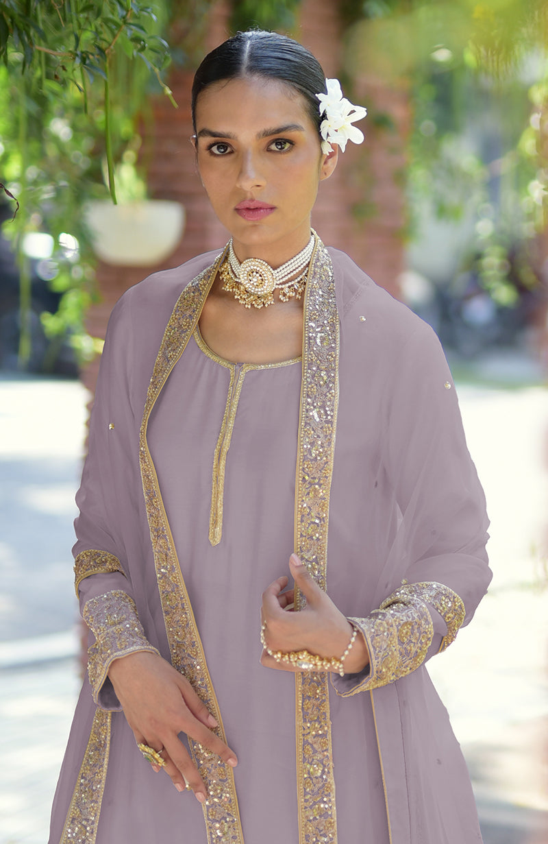 Woman in a lavender kurta set with gold embroidery and a pearl choker.